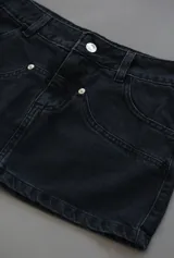 Mini falda de jean color negro con tiro bajo.