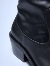 Bota de cuero negra con caña elastizada, punta cuadrada y taco geométrico.