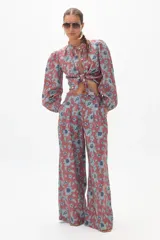 Conjunto de pantalón y blusa de lino con estampado floral en tonos terracota y azul. La blusa es de manga larga con cuello mao y se ata en la parte delantera. El pantalón es culotte de tiro alto con bolsillos laterales y cierre frontal escondido.