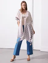 Kimono tejido con estampado abstracto en tonos beige, blanco y negro. Tiene mangas amplias estilo japonés y terminación de ruedo con borlas.