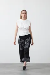 Pantalón de denim azul oscuro con bordado estilo bandana en blanco en los laterales de las piernas y en los puños. El corte es recto y amplio, llegando al tobillo.