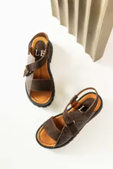 Sandalias de cuero color marrón y blanco, con suela track negra y ajuste con velcro.