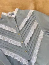 Camisa blanca de mangas largas con cuello alto y detalles de encaje.