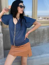 Camisa de gasa color gris oscuro, con mangas globo y una tira central vertical decorada con piedras azules.