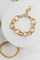 Pulsera dorada de eslabones grandes, algunos texturizados y otros lisos, con cierre de mosquetón y cadena de extensión.