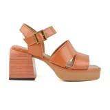 Sandalias de cuero color suela, con plataforma y taco cuadrado de madera. Tiras anchas cruzadas sobre el empeine y pulsera con hebilla metálica.