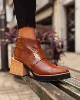 Bota corta de cuero color marrón con puntera en punta y cierre lateral con cremallera.