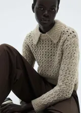 Sweater beige de punto calado con cuello polo y terminaciones acanaladas.