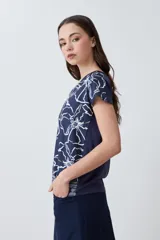 Blusa azul marino con estampado floral en blanco y ocre, de corte recto y mangas cortas.