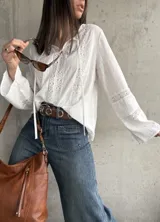 Blusa blanca de manga larga con detalles de encaje en el frente, mangas y cuello.