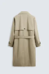 Trench largo regular fit color beige confeccionado en tejido italiano repelente al agua. Tiene cuello con solapas de pico, manga larga con puño ajustable con trabilla, bolsillos de vivo en cadera, bolsillo interior, cinturón del mismo tejido en cintura, bajo con abertura en centro espalda y cierre frontal de botonadura cruzada.
