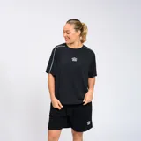 Remera negra de corte holgado con cuello redondo y mangas cortas con doble línea blanca en los hombros. Logo de Umbro estampado en blanco en el pecho.
