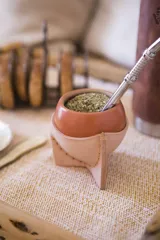 Mate de cerámica con diseño atractivo, acompañado de un posamate de cuero color cobre.