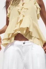 Top color rosa viejo de cuello halter ajustable con lazadas. Detalle de abertura en el delantero y volantes en el mismo tejido.