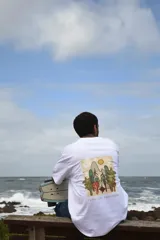 Remera celeste de algodón con estampa rectangular en la espalda que representa un paisaje de bosque con montañas, árboles y el sol. Incluye la frase 'Time to recreate'.