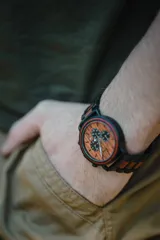 Reloj multifuncional para hombre, con caja de madera de sándalo rojo y acero inoxidable negro. La esfera es de madera de sándalo rojo con subdiales negros funcionales que ofrecen cronógrafo, indicador de 24 horas y fechador. La malla es de acero inoxidable negro con incrustaciones de madera de sándalo rojo.