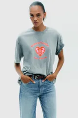 Camiseta rosa de algodón con efecto lavado, corte regular, cuello redondo y mangas cortas. Estampado frontal con la frase "Puerto Rico Vuela Conmigo".