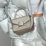 Cartera bandolera color peltre, con diseño acolchado en símil cuero y costuras a tono. Tiene acceso con solapa, correa regulable y asa fija. Cuenta con un bolsillo interno con cierre y un bolsillo externo abierto.