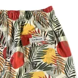 Short de baño con estampado de hojas de palmera y círculos rojos.