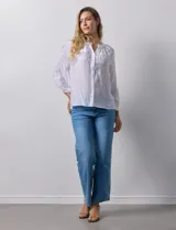Blusa blanca de gasa bambula con cuello a la base y apertura central con botones. Apliques de crochet en la parte delantera y en las mangas ¾ con terminación fruncida.
