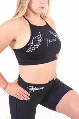 Top deportivo negro con estampado de alas y texto en blanco.