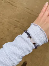 Pulsera elástica con cuentas de piedra negra irregulares y una cuenta central cilíndrica de color verde agua.