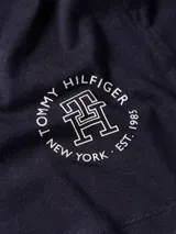 Remera azul marino de cuello redondo y manga corta, confeccionada en algodón. Presenta un logo de Tommy Hilfiger en el lateral inferior.