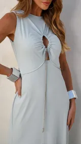 Vestido largo celeste con corte a la cintura, escote redondo con abertura circular y cadena metálica decorativa.