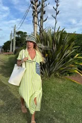 Túnica larga con cuello tipo camisa, de lino a rayas verticales verdes y blancas, con bordado azul en el frente.