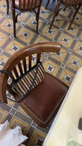 Bolso de mano tipo clutch o cartera pequeña, tejido a mano en cuero. Presenta un diseño de rayas diagonales alternando colores negro, marrón y beige claro.