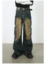 Pantalón de jean ancho (baggy) con lavado oscuro y efecto desgastado en tonos marrones/ocre. Presenta múltiples bolsillos cargo grandes con tapa y botones a presión en las piernas.