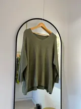 Sweater verde seco de corte recto con escote en pico y detalle de brillo sublimado.