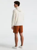 Campera rompevientos color crema con cierre frontal, cuello alto, capucha oculta, puños elásticos y bolsillos laterales con cierre.
