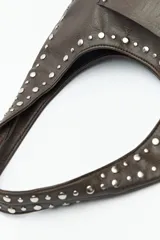 Cartera negra tipo hobo de cuero sintético con apliques de tachas metálicas plateadas en el frente y los bordes.