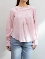 Blusa rosa claro de algodón con escote cuadrado, manga larga y bordado floral en el frente y las mangas.