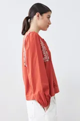 Remera blanca de estilo boho con bordados en el escote y mangas largas. Presenta escote en V con lazos y borlas. Corte recto y holgado.