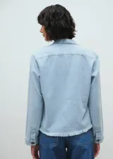 Campera de jean celeste claro, corte crop, con cuello clásico, cierre frontal con botones, mangas largas, dos bolsillos frontales y ruedo desflecado.