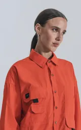Camisa naranja de manga larga, estilo técnica con múltiples bolsillos delanteros y un bolsillo en la parte inferior de espalda, botones en cartera y mangas, calce oversize.