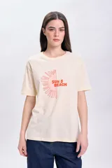 Remera color crema de corte recto, con mangas cortas y estampa de medio sol con el texto "Sun & Beach" en color naranja.