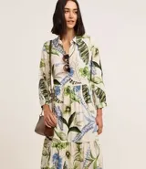 Vestido chemise midi confeccionado en viscosa sostenible, con cuello, abotonadura frontal, recorte en la cintura y bajo fruncido. Presenta un estampado floral con follajes.