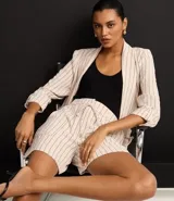 Short de cintura alta color crema con rayas verticales finas en azul marino, con bolsillos laterales y cintura elástica ajustable con lazo.