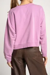 Sweater lila de algodón, corte holgado, con cuello redondo y mangas largas.