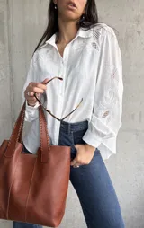 Camisa blanca de manga larga con detalles bordados en el cuello y los puños.