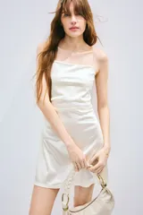 Vestido corto de breteles finos color blanco, con escote recto y frunces laterales que generan un efecto drapeado.