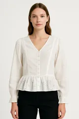 Blusa blanca de algodón con escote en V, mangas largas con puños elásticos y detalle de bordado calado.