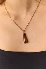 Collar dorado con cadena fina y dije colgante en forma de lágrima de piedra natural azul con vetas blancas.