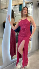 Vestido largo de fiesta fucsia con lentejuelas, escote halter, espalda descubierta y tajo lateral.