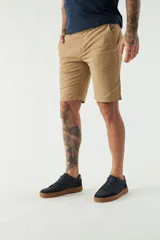 Bermuda de gabardina color beige, corte chino, con bolsillos laterales y traseros, cierre con cremallera y botón, presillas para cinturón y logo bordado.