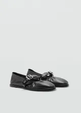 Zapato tipo bailarina color dorado, con punta redonda y tira sobre el empeine con hebilla metálica.