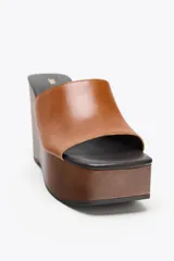 Sandalias de cuña color marrón con plataforma de madera y tira ancha de cuero sintético color caramelo.